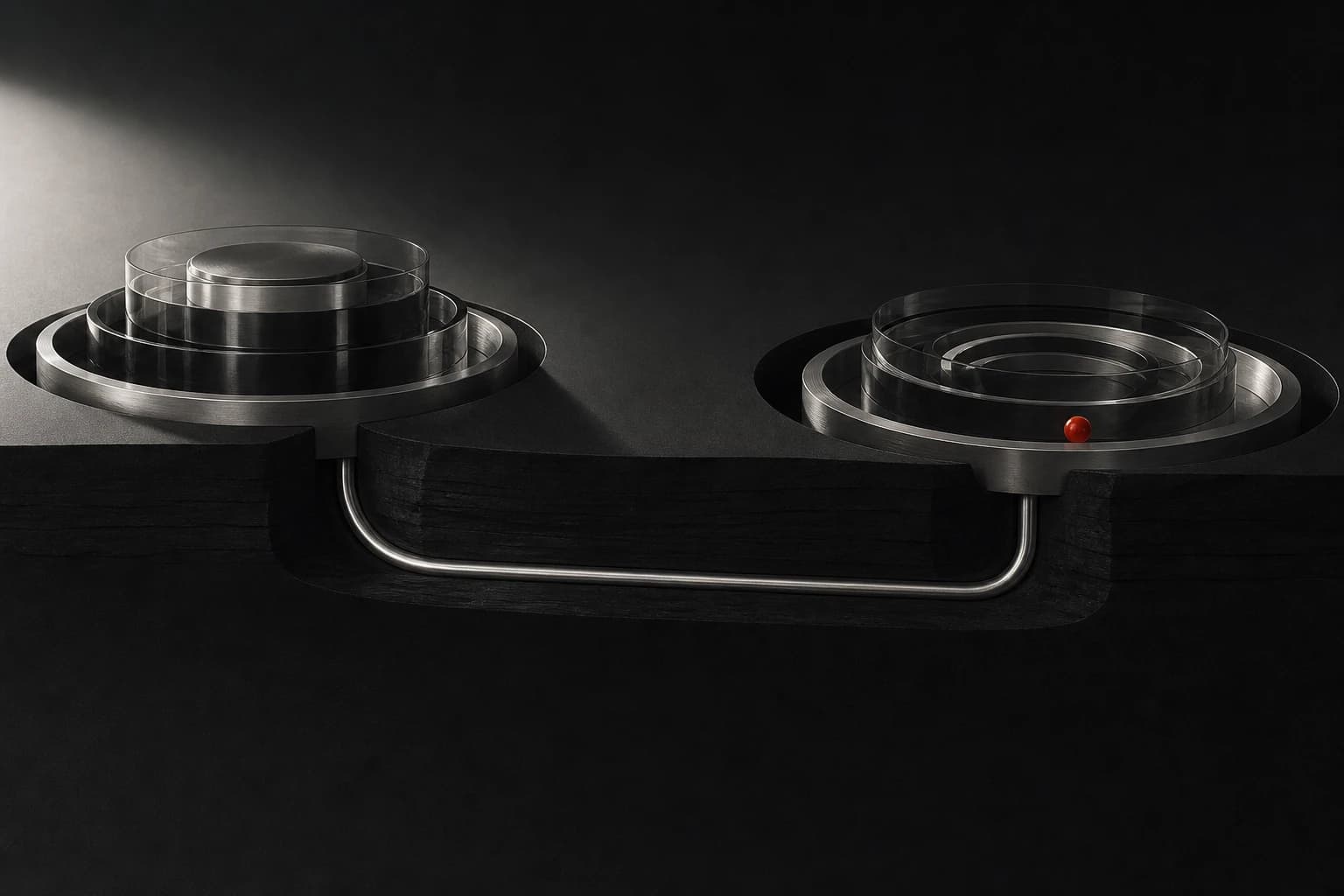 Two isolated silver and glass chambers are secretly joined below a dark surface, with one small red bead inside the second chamber